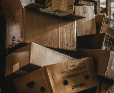 Stacks of cardboard boxes in a warehouse, representing how inventory decisions can grow as demand signals move through a supply chain.