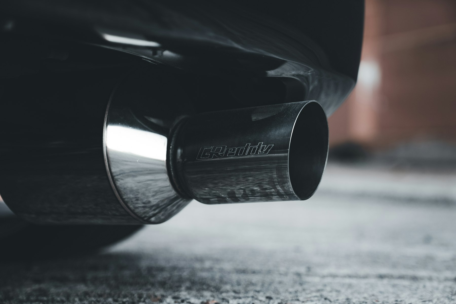 A close view of a car exhaust pipe where gases leave after passing through emission-control parts.