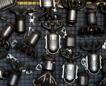 Catalytic converters and exhaust components arranged on a workshop wall for vehicle emissions repair.