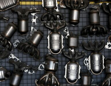 Catalytic converters and exhaust components arranged on a workshop wall for vehicle emissions repair.