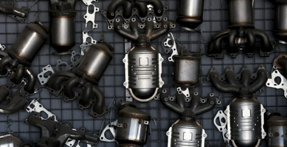 Catalytic converters and exhaust components arranged on a workshop wall for vehicle emissions repair.
