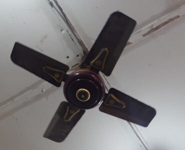 A four-blade ceiling fan mounted above an indoor room