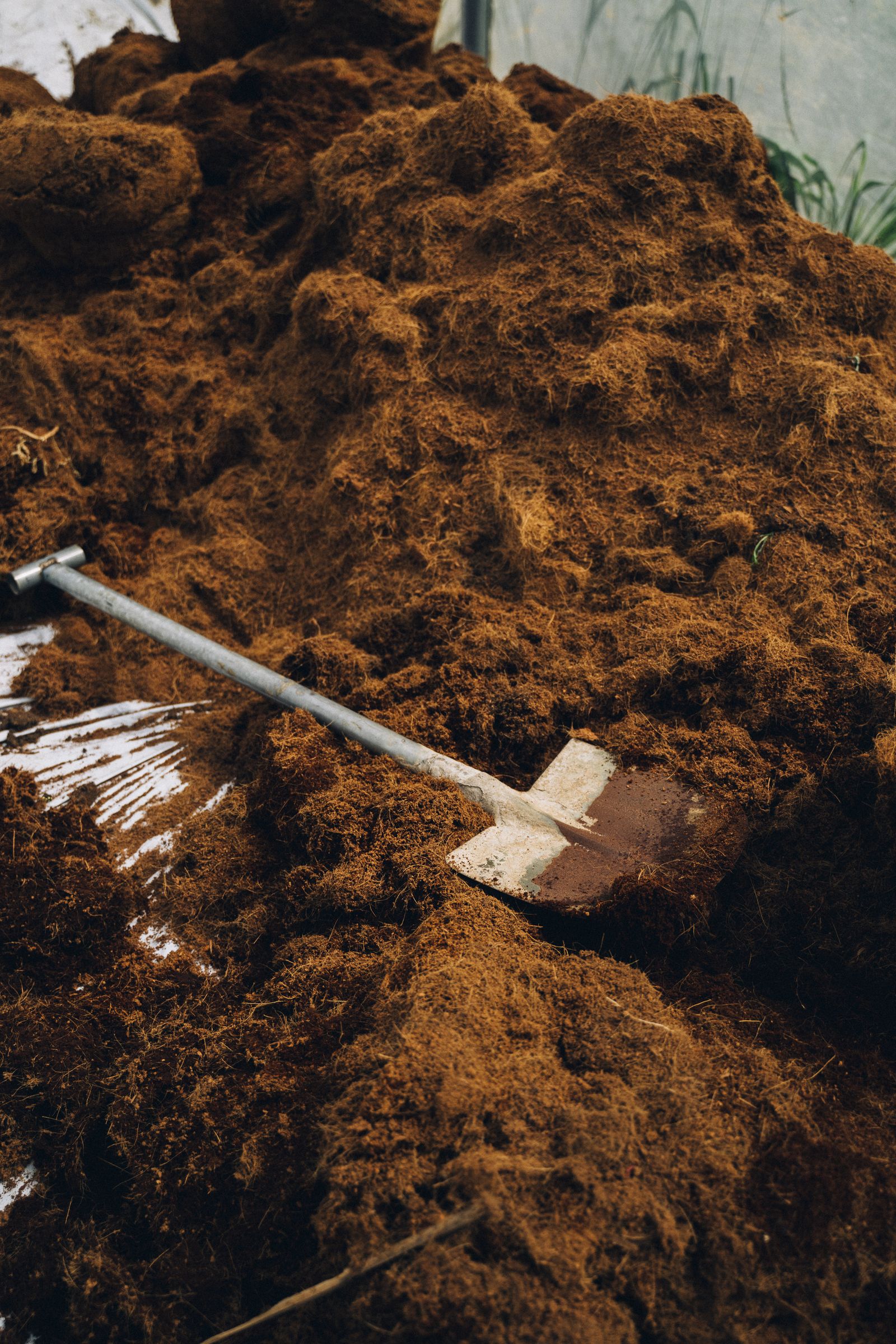 A shovel rests in dark soil that can be improved with finished compost.