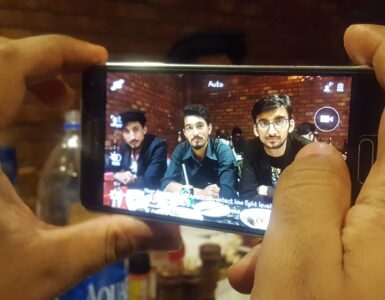 A smartphone camera being used in low light, where software can combine several frames into one clearer photo.