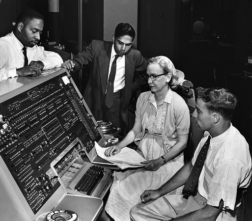 Grace Hopper standing beside UNIVAC-era computer equipment