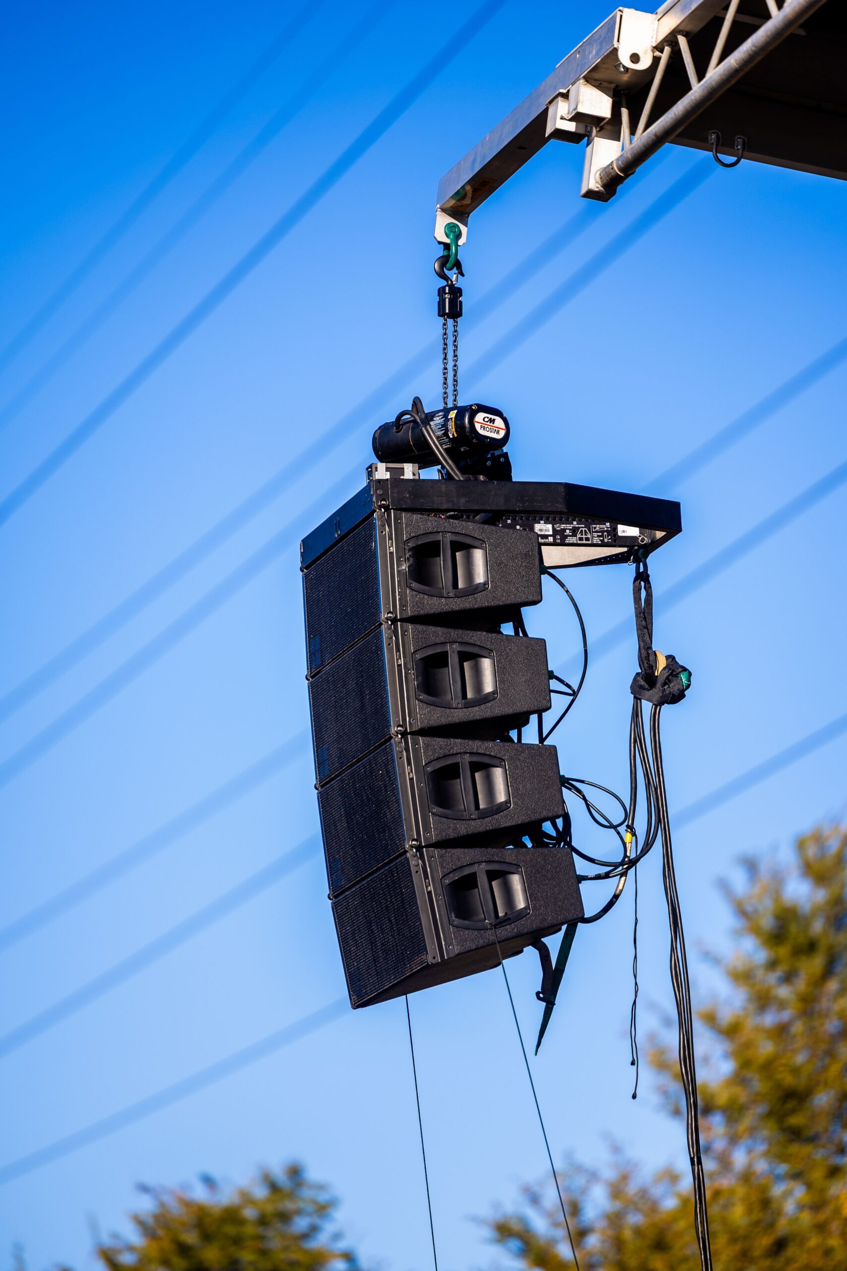 A hanging line array speaker system being raised for an outdoor concert