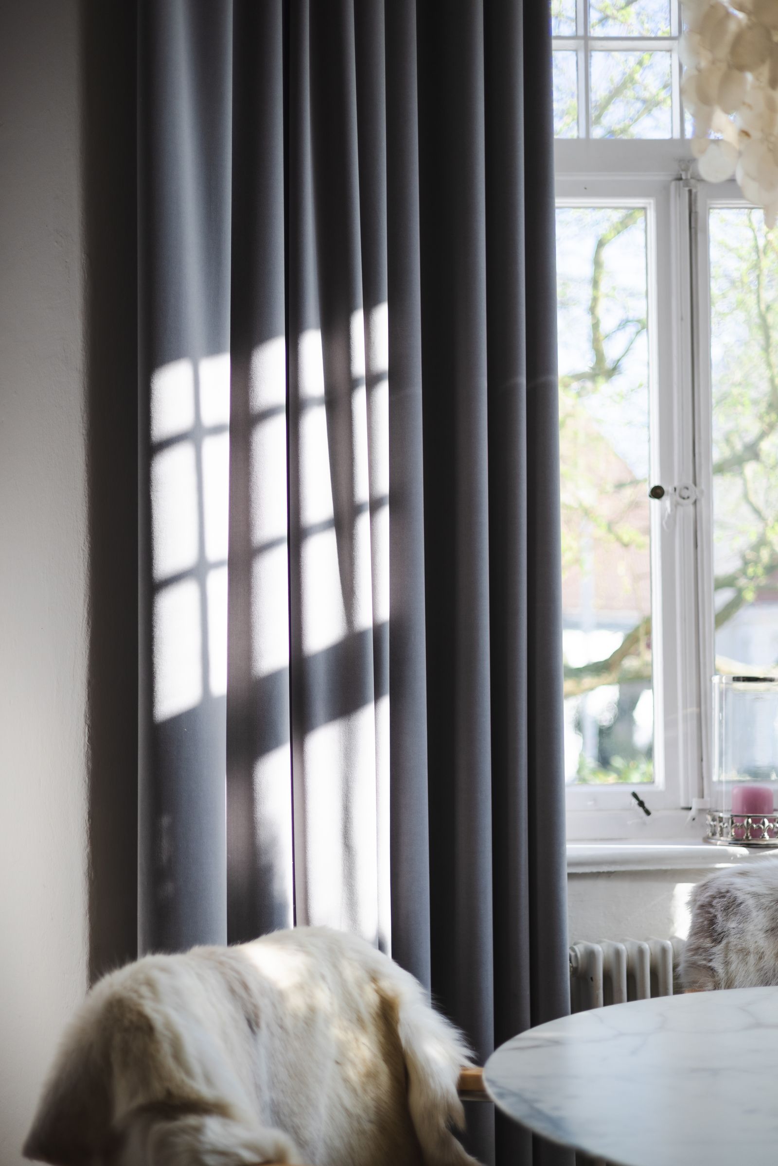 Living room curtains filtering bright daylight through large windows