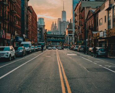A New York City street lined with tall buildings in warm sunset light