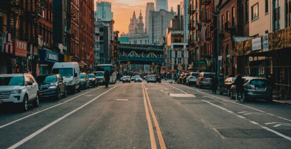 A New York City street lined with tall buildings in warm sunset light