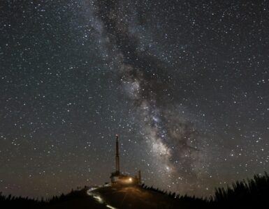 The Milky Way stretching across a dark sky above a hilltop observatory