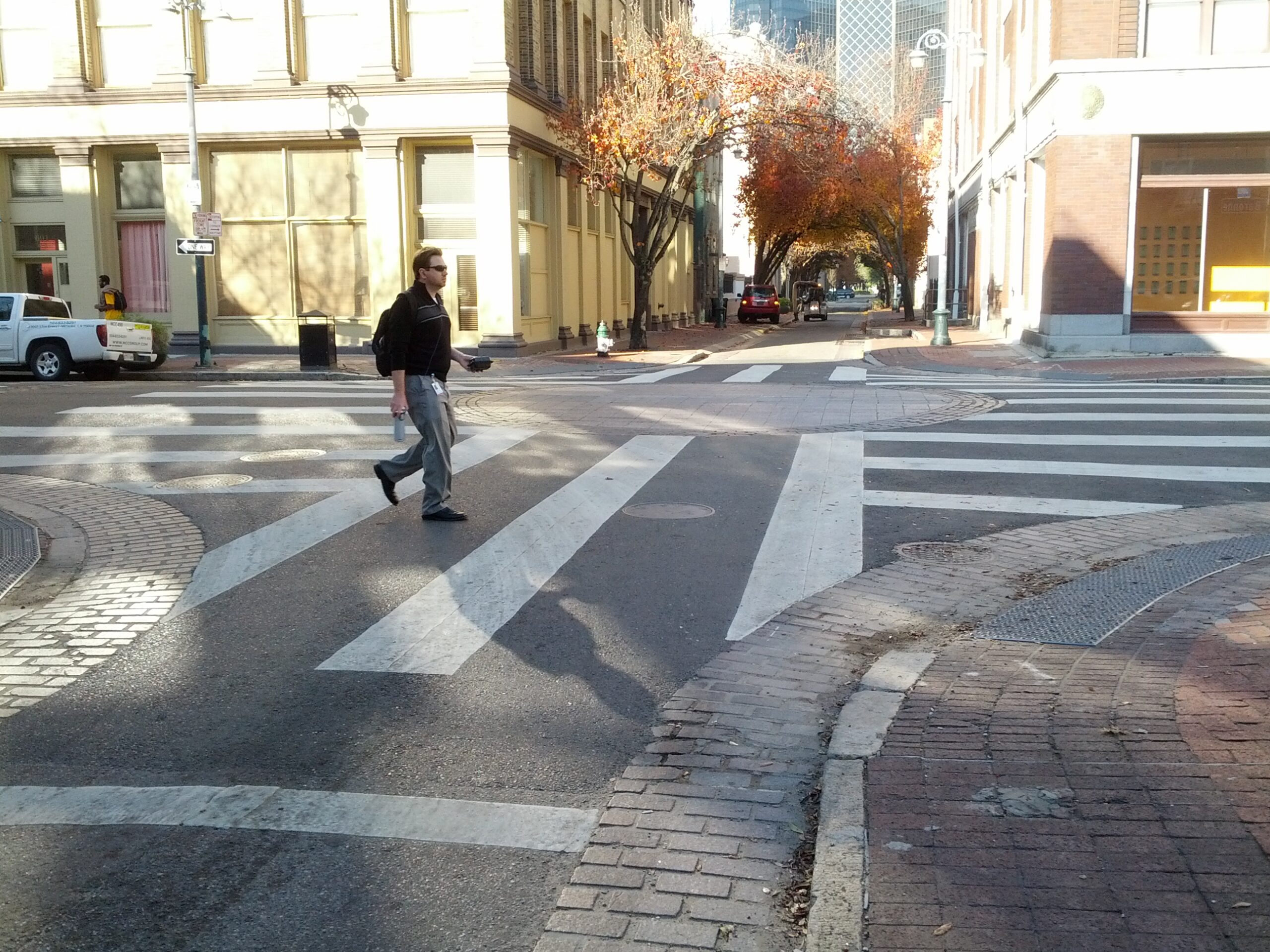 Mini roundabout with wide crosswalk stripes at a city intersection.