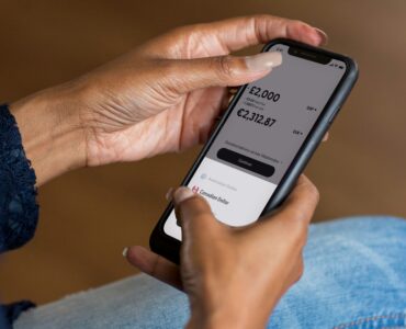 A person checking a mobile banking app, representing account balances and overdraft risk