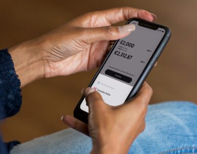A person checking a mobile banking app, representing account balances and overdraft risk