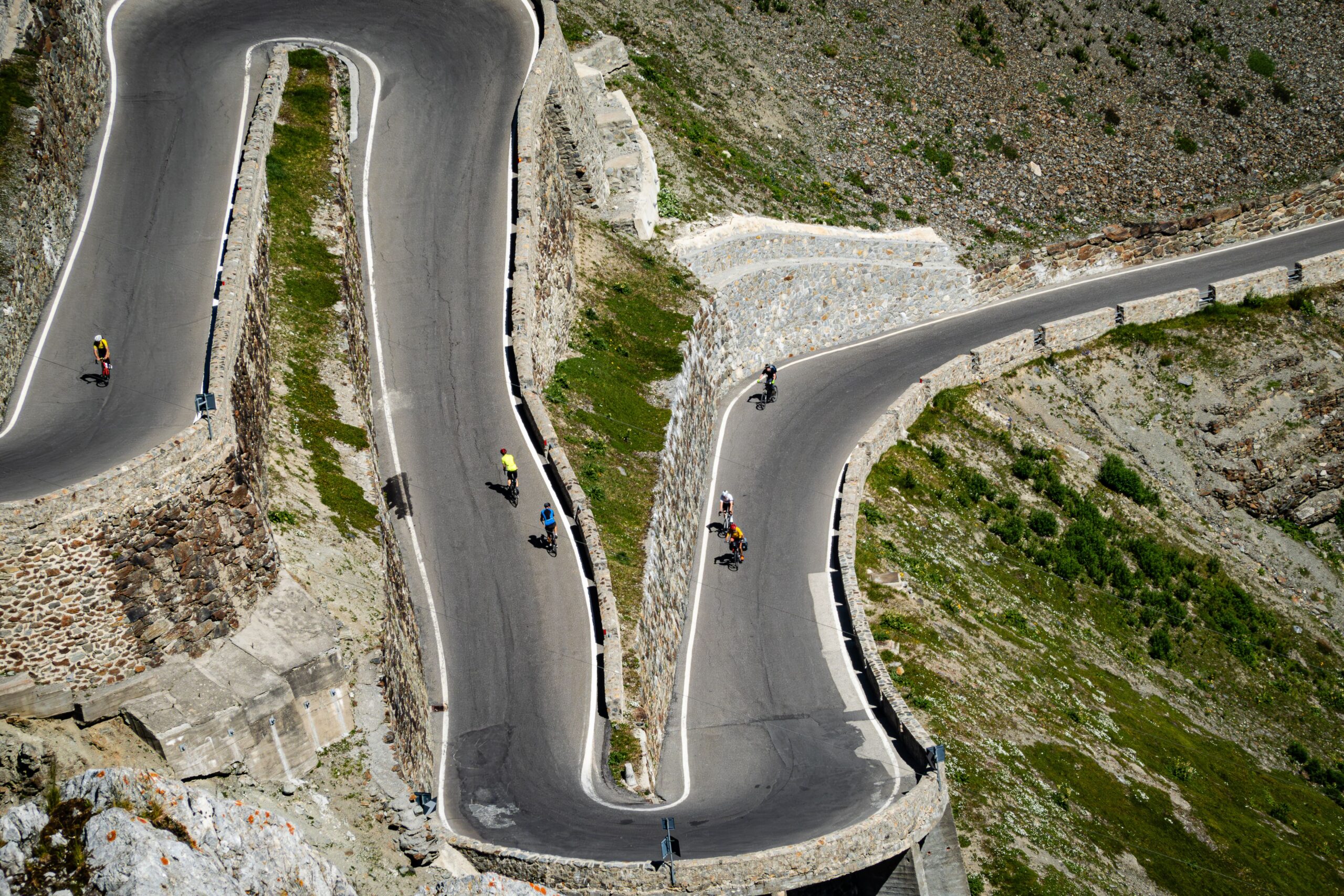 Cyclists riding through sharp hairpin turns on a mountain road