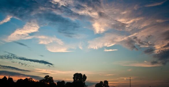 Pale clouds glowing in blue and orange twilight, similar to the evening conditions when noctilucent clouds are easiest to spot.