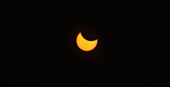A partial solar eclipse with the Moon covering part of the Sun against a dark sky.