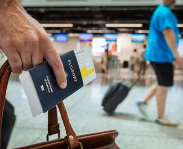 A traveler holding a U.S. passport and boarding pass inside an airport terminal.