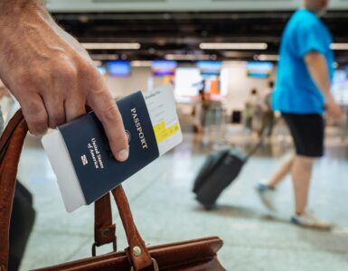 A traveler holding a U.S. passport and boarding pass inside an airport terminal.