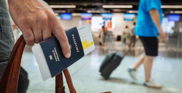 A traveler holding a U.S. passport and boarding pass inside an airport terminal.
