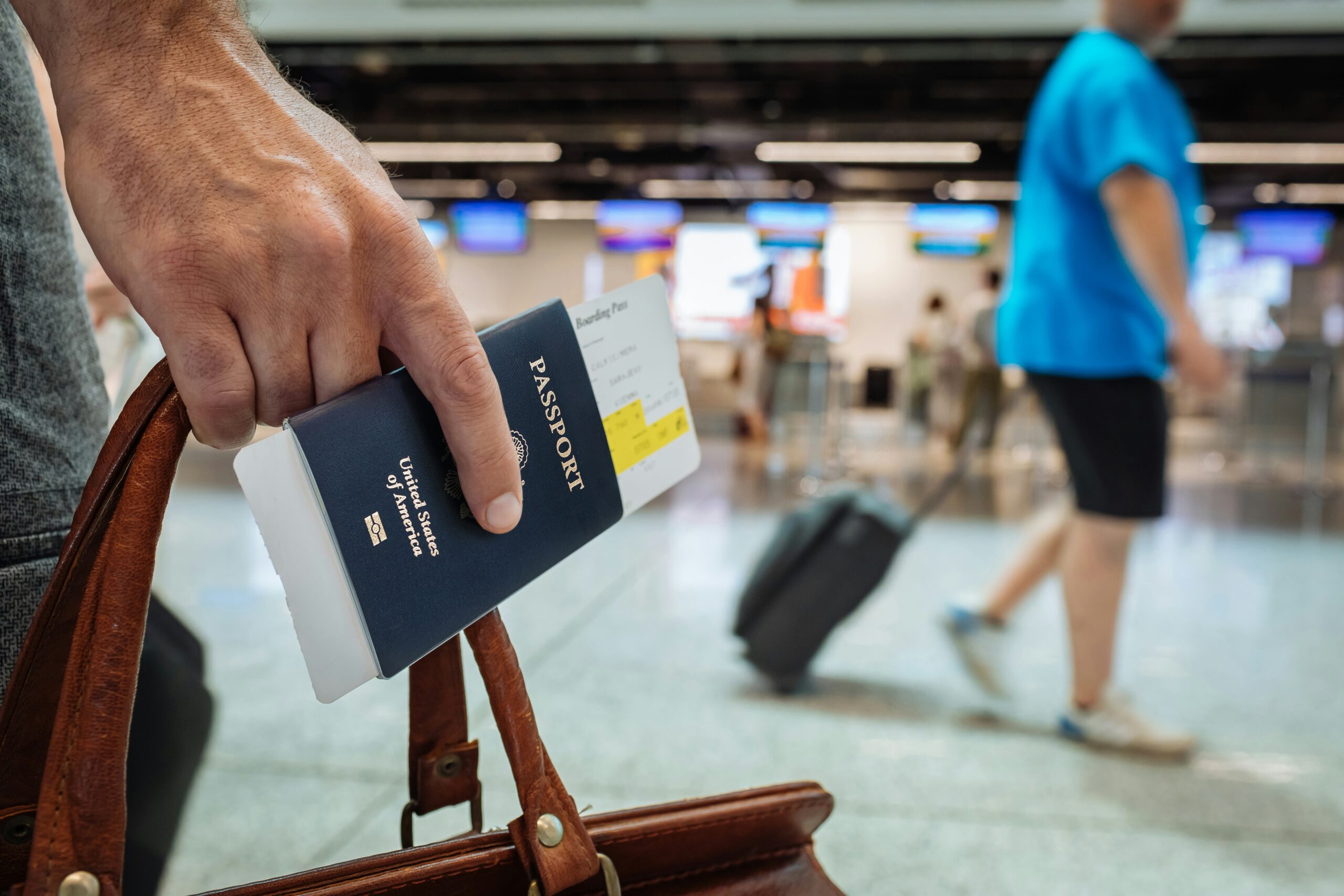 A traveler holding a U.S. passport and boarding pass inside an airport terminal.