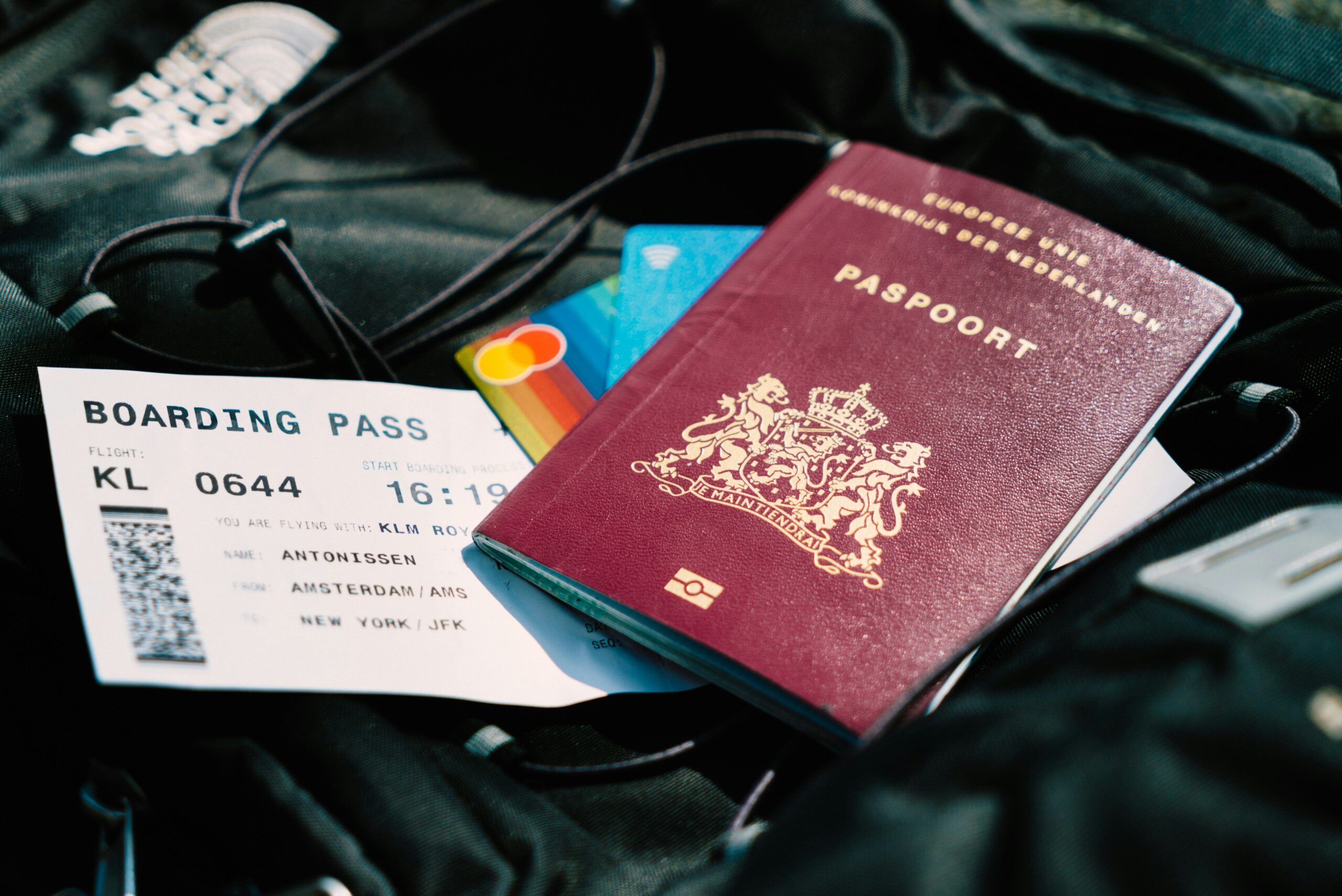 A passport and boarding pass arranged on a travel bag before a flight.