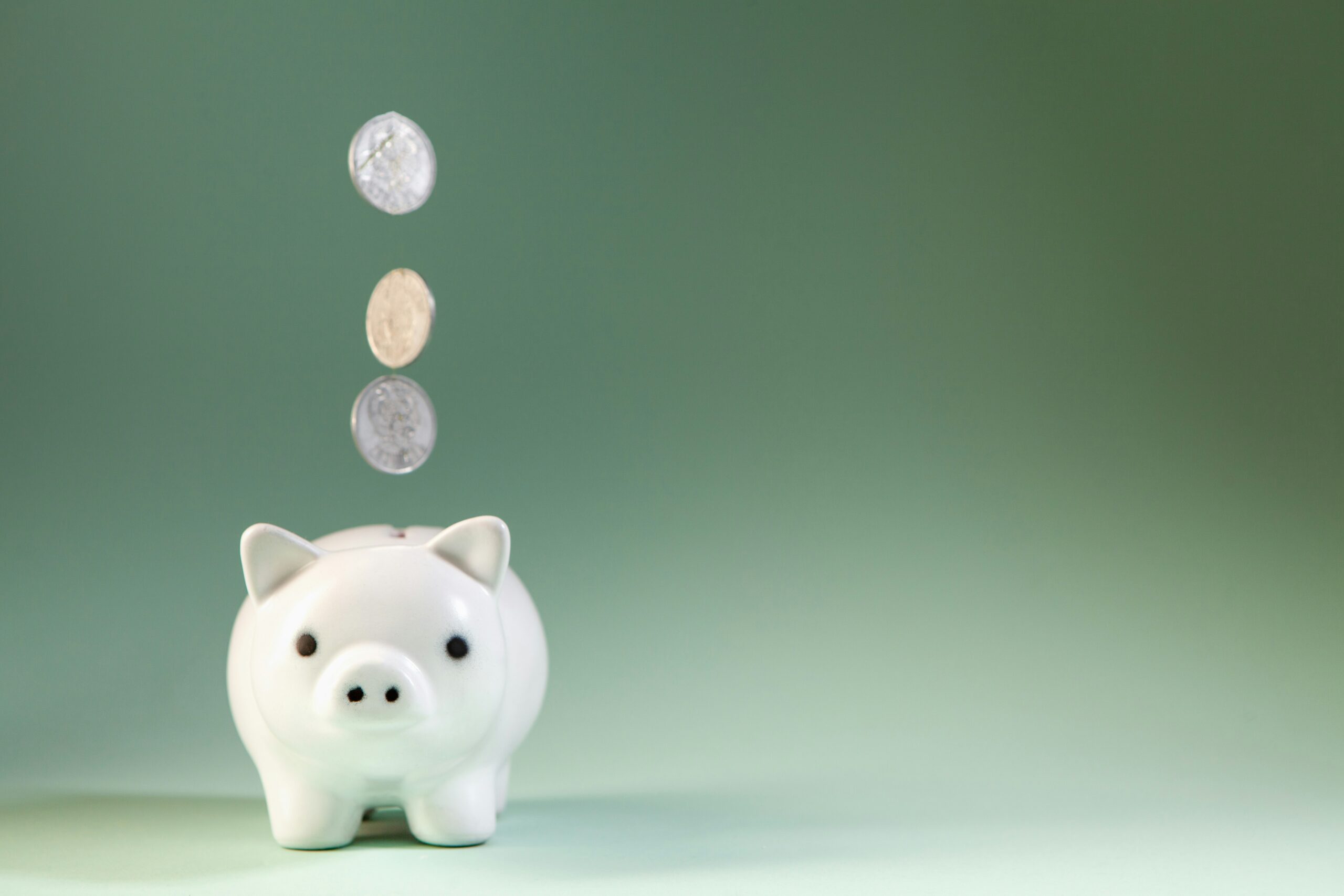Coins falling into a piggy bank, representing a small balance cushion to prevent overdraft fees