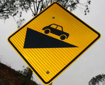 A retroreflective road sign photographed in daylight, showing how warning signs are built to return headlight beams at night.