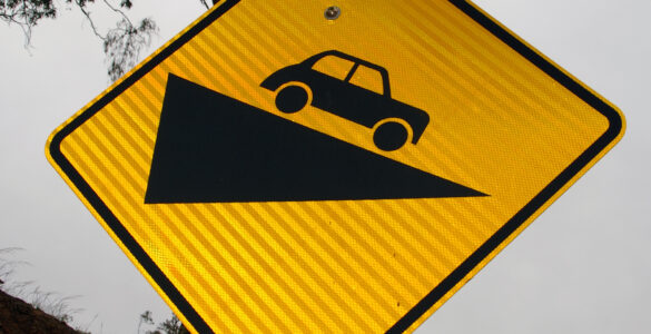 A retroreflective road sign photographed in daylight, showing how warning signs are built to return headlight beams at night.