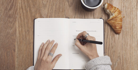 A journal and pen on a desk for studying rhyme schemes in poetry.