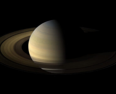 Saturn and its bright rings seen with several small moons nearby.