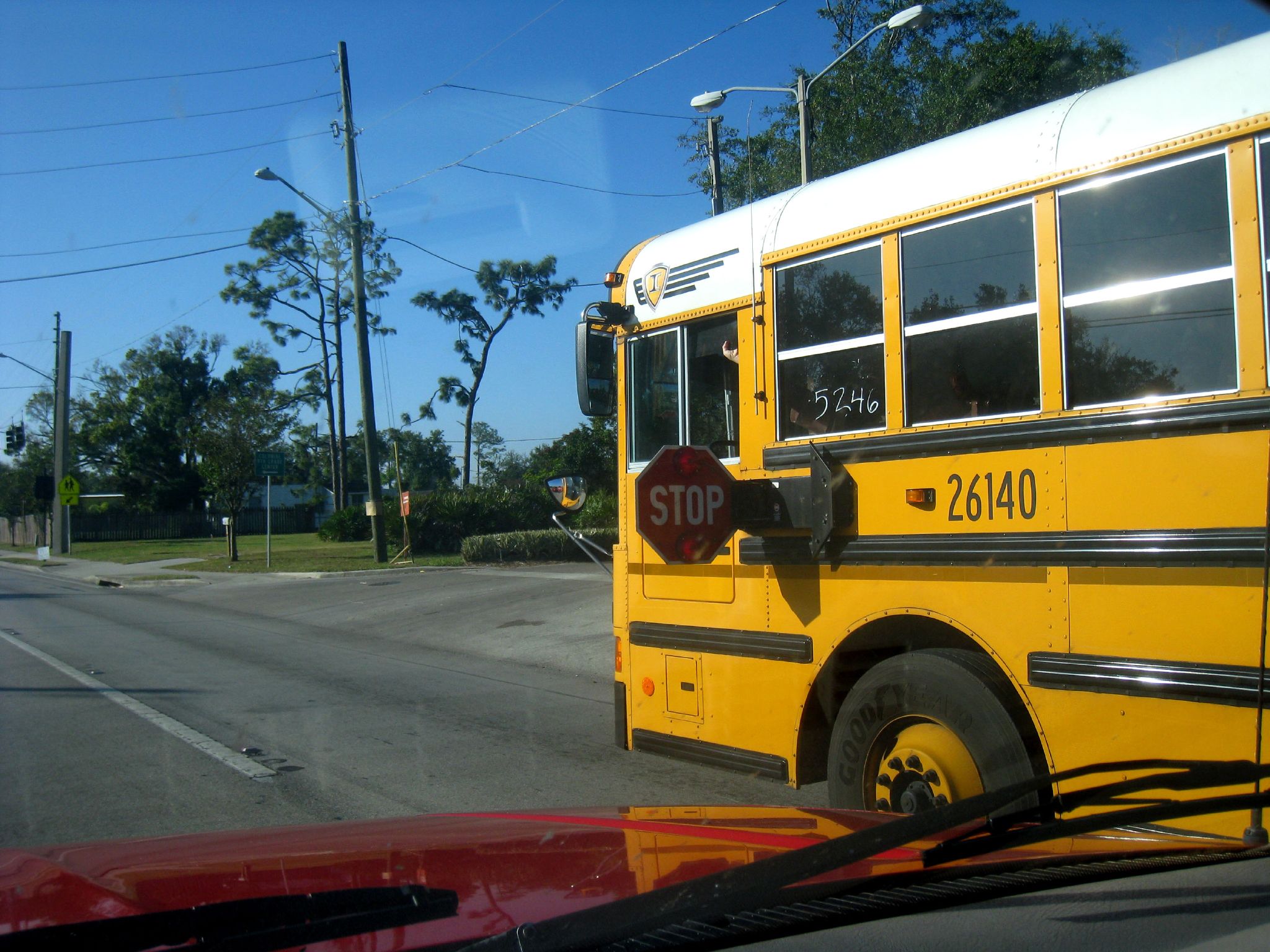 A yellow school bus with its stop arm extended beside a road