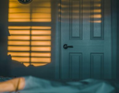 An alarm clock beside a bed in morning light, representing grogginess after waking.