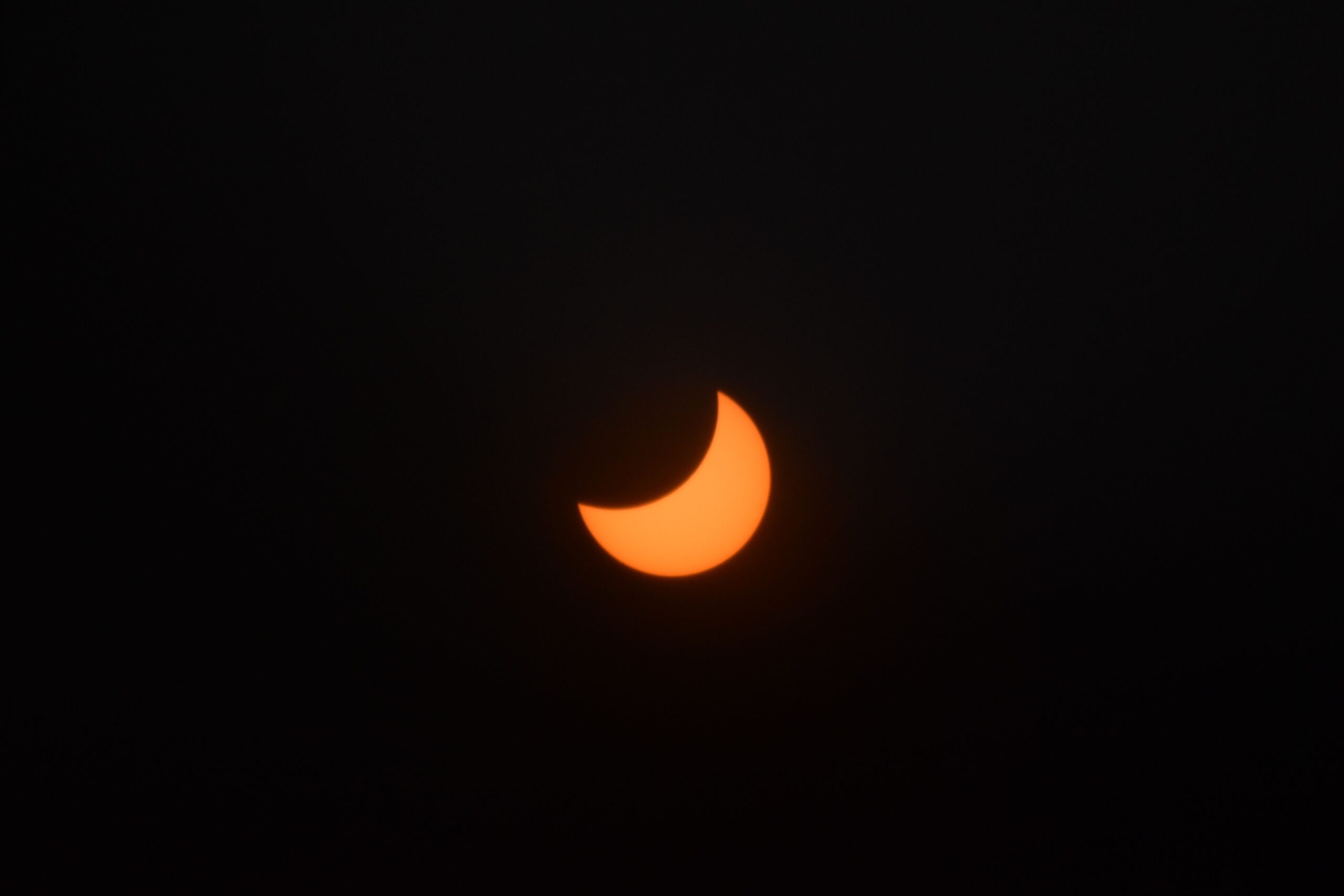 A crescent-shaped Sun during a solar eclipse against a dark background.