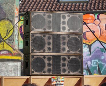Large speaker stacks facing a crowd at an outdoor concert