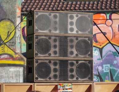 Large speaker stacks facing a crowd at an outdoor concert