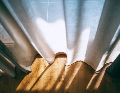 Sunlight streaming through white curtains near a window on a warm day
