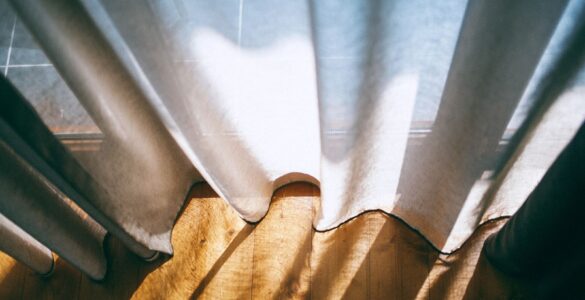Sunlight streaming through white curtains near a window on a warm day