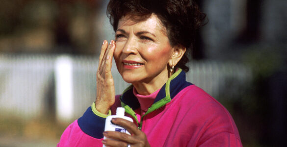 A person applying sunscreen outdoors before spending time in the sun