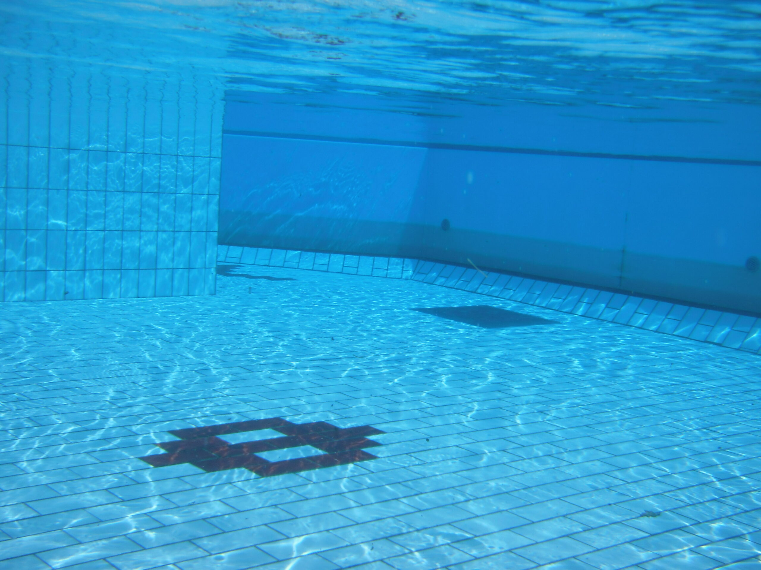 An underwater view in a swimming pool where the blue tint becomes stronger through more water.