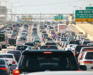 Heavy highway traffic backing up before a merge point where a zipper merge can shorten the queue.