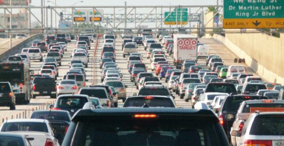 Heavy highway traffic backing up before a merge point where a zipper merge can shorten the queue.