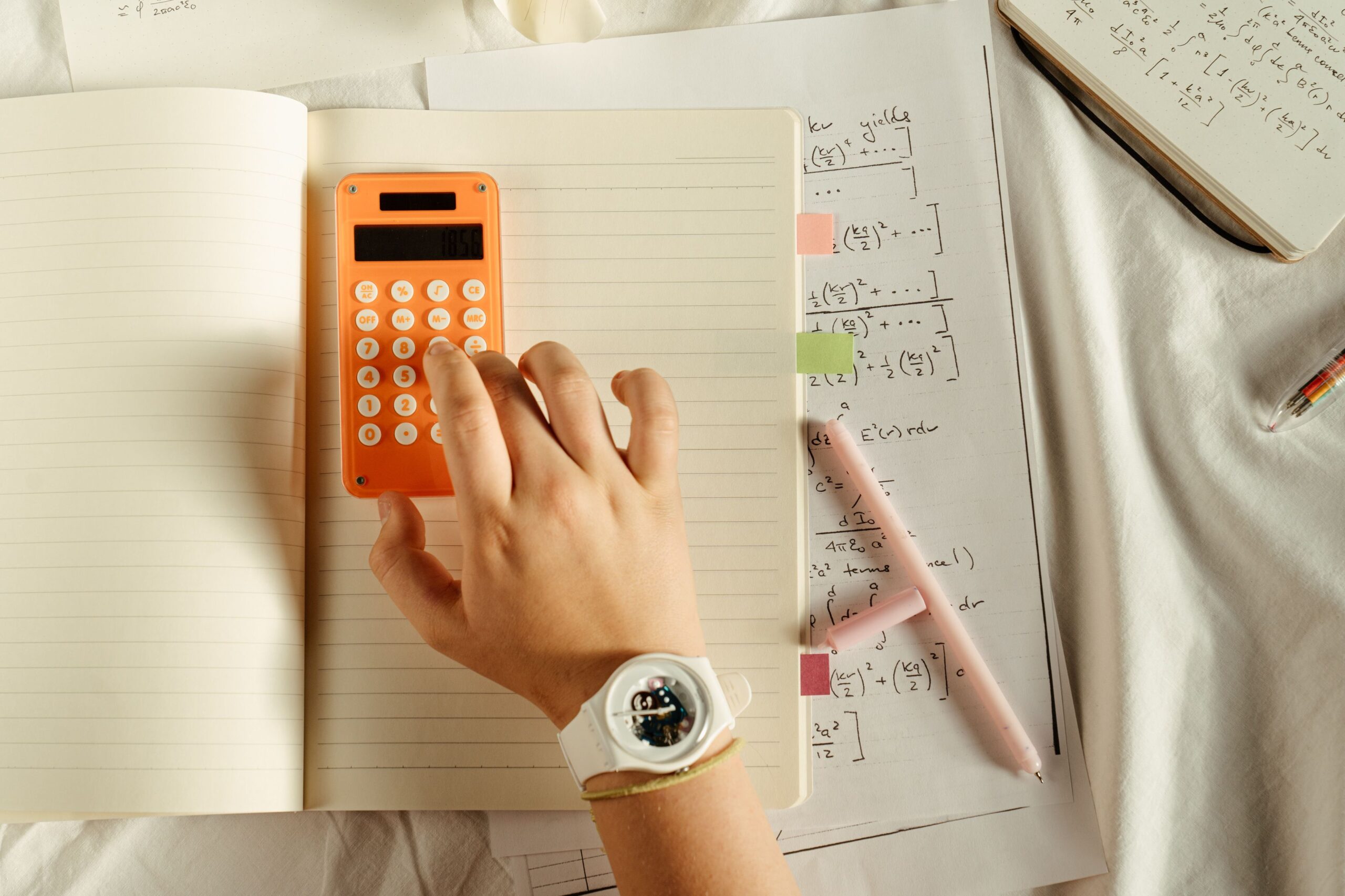 A student uses a calculator beside handwritten notes while checking arithmetic sequence formulas.