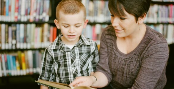 Two readers discuss a book in a library, representing shared access to ideas and reading choices.