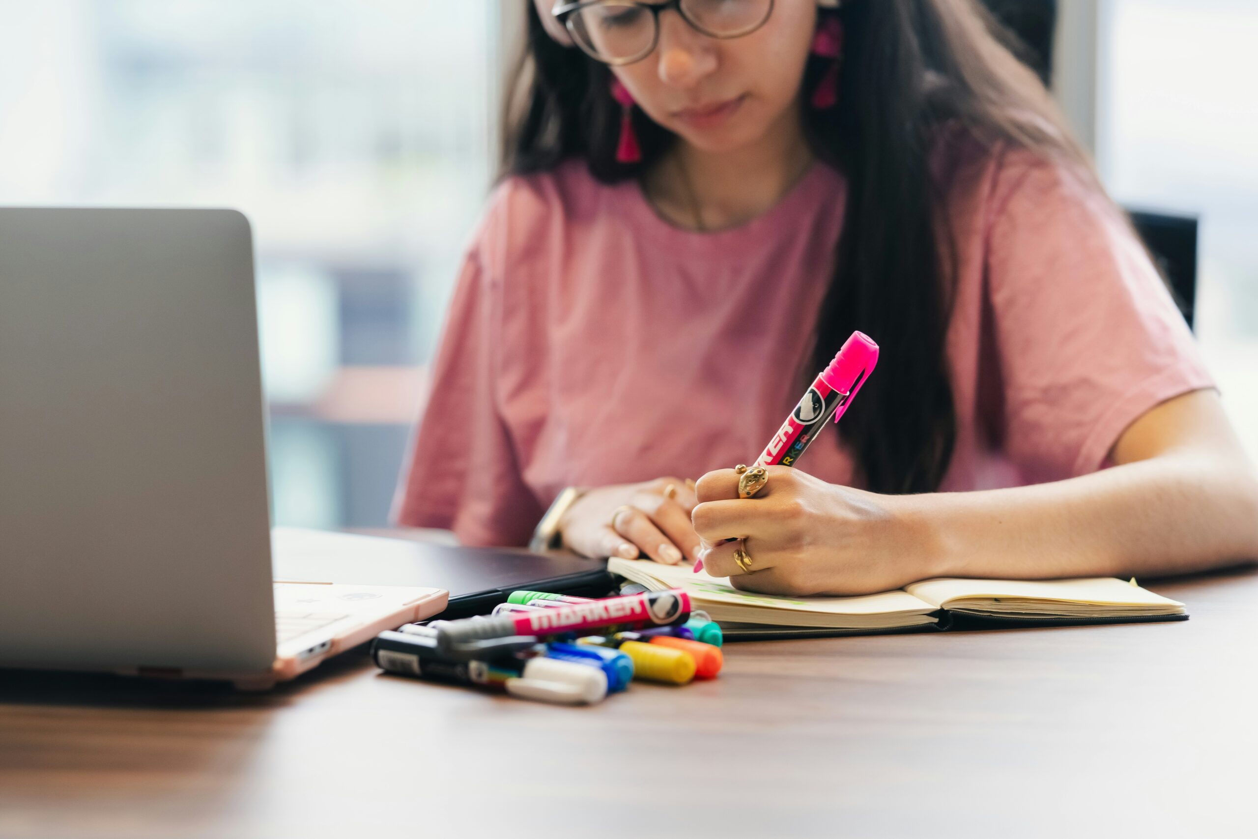 A student writes notes beside a laptop while preparing for a digital AP exam format.