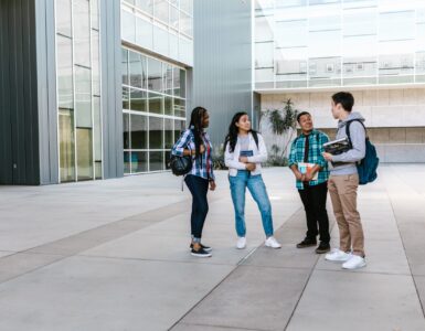 College students walking near a campus building while planning how to request academic accommodations before classes start.