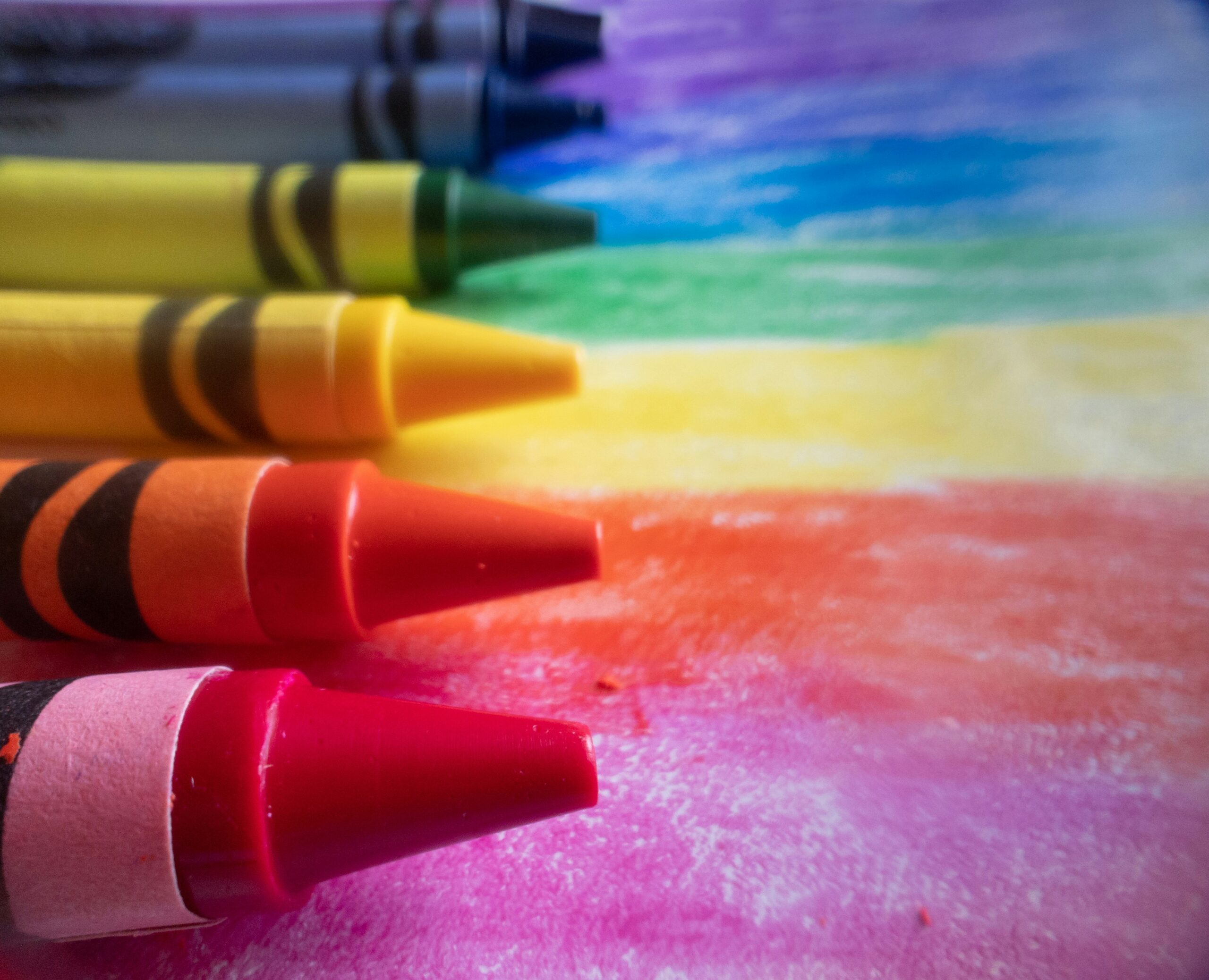Close-up of crayons and colorful wax strokes showing how pressure leaves uneven color on paper texture.