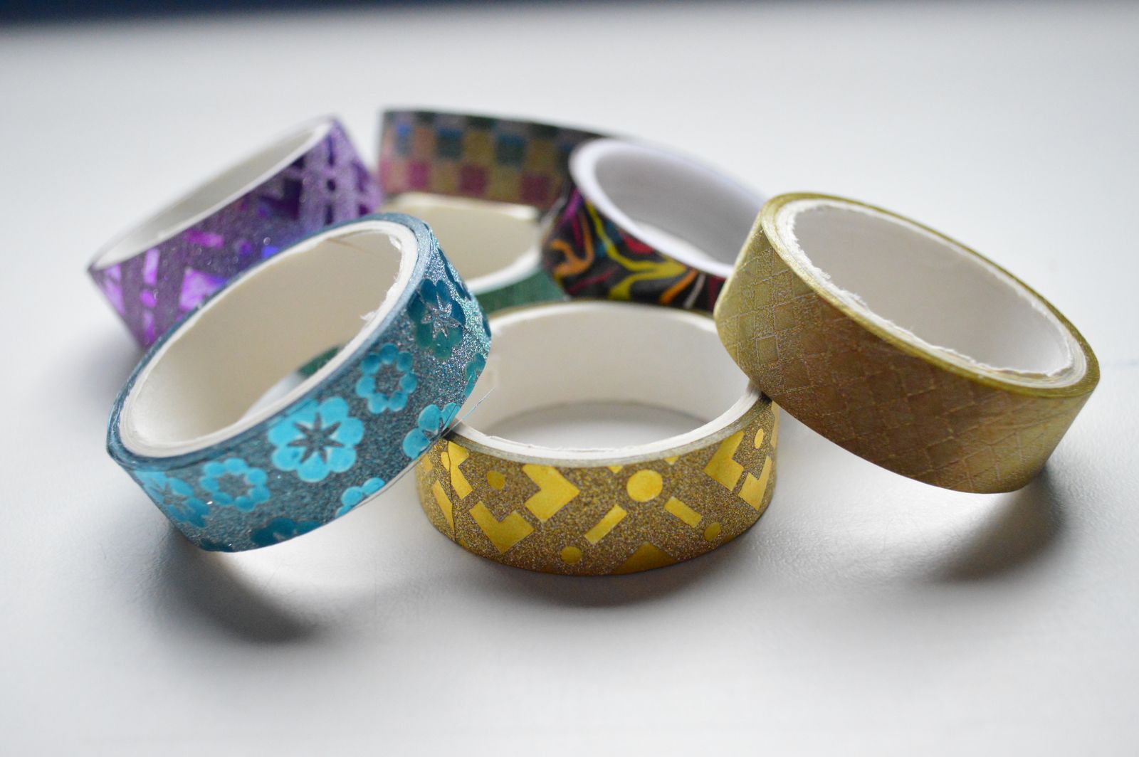 Colorful rolls of decorative adhesive tape arranged on a table, illustrating flexible pressure-sensitive adhesives.