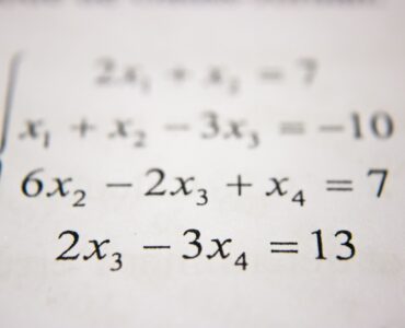 A student works through algebra steps on a whiteboard while practicing the distributive property.