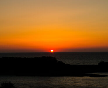 The Sun sits on the horizon at sunrise, showing why the visible edge matters when measuring daylight.
