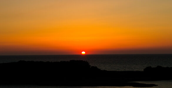The Sun sits on the horizon at sunrise, showing why the visible edge matters when measuring daylight.